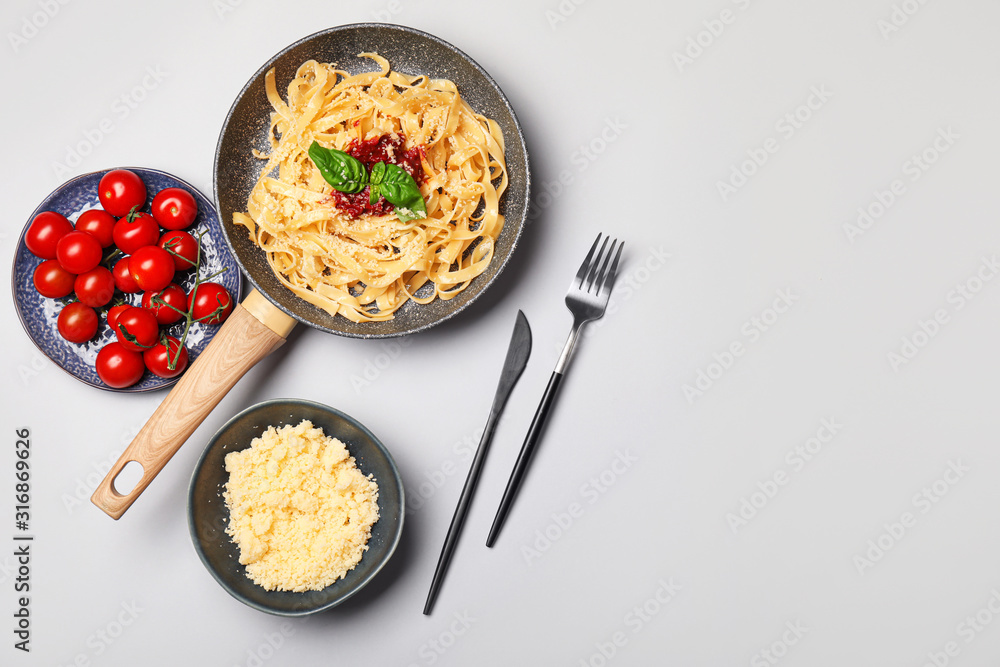 Frying pan with tasty pasta, tomato sauce and cheese on white background Frying pan with tasty pasta, tomato sauce and cheese on white background