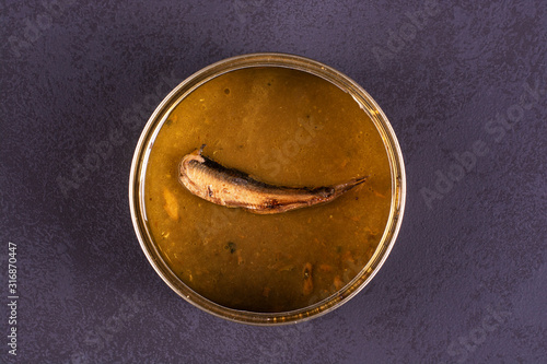 Open empty tin can of sprats on a dark background.