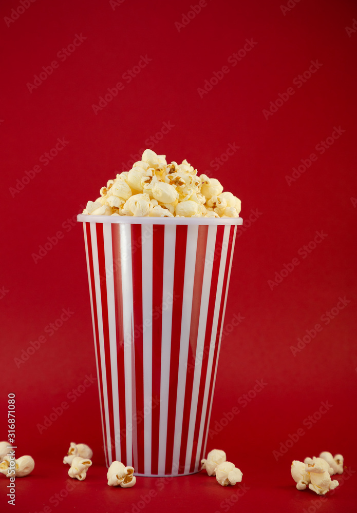 Butter popcorn in a red popcorn cup, snack in the house or cinema on a red background Butter popcorn in a red popcorn cup, snack in the house or cinema on a red background