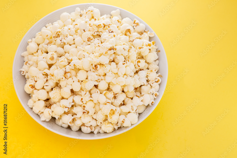 Butter popcorn in a red popcorn cup, snack in the house or cinema on a yellow background Butter popcorn in a red popcorn cup, snack in the house or cinema on a yellow background