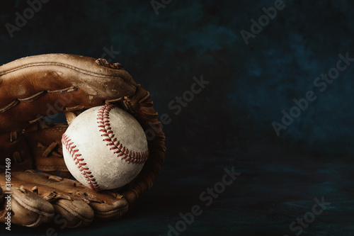Canvas Print Moody style baseball background with old ball in leather glove close up for sport, copy space on dark backdrop