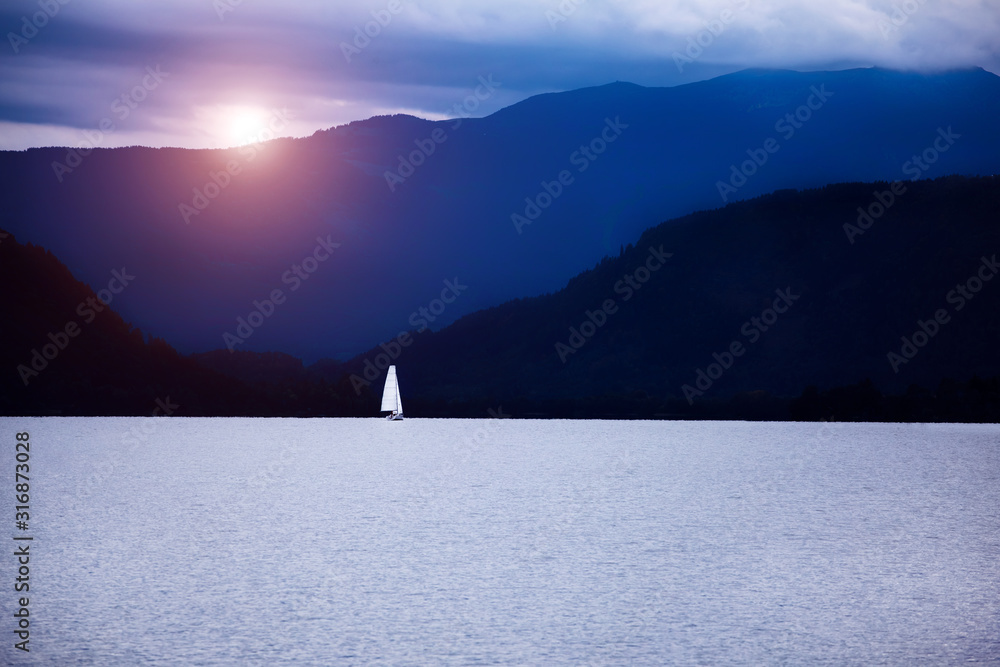 Magical scenery with sailboat on lake in sunrise light