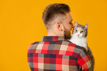 Man with cute cat on color background