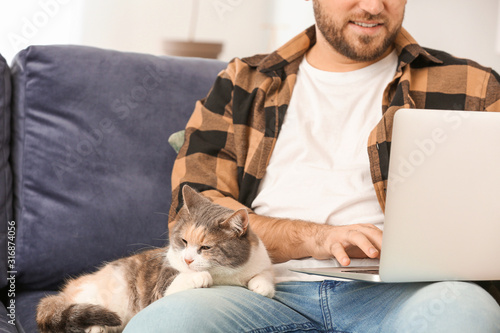 Man with cute cat using lap...