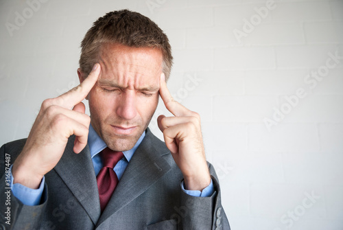 Photography Stressed businessman rubbing his temples with eyes closed to alleviate his heada