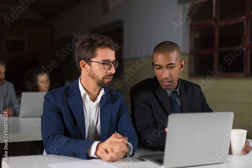 Two handsome young businessmen looking at laptop and talking. Business partners working with laptop. Business, working late concept