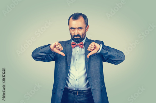 angry, unhappy, mature man showing thumbs down sign