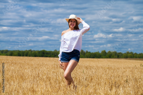 Young brunette woman in white shirt and blue jeans shorts © Andrey_Arkusha