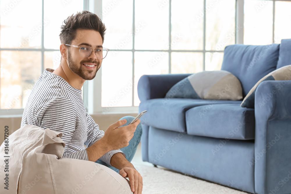 Happy young man with mobile phone at home Happy young man with mobile phone at home