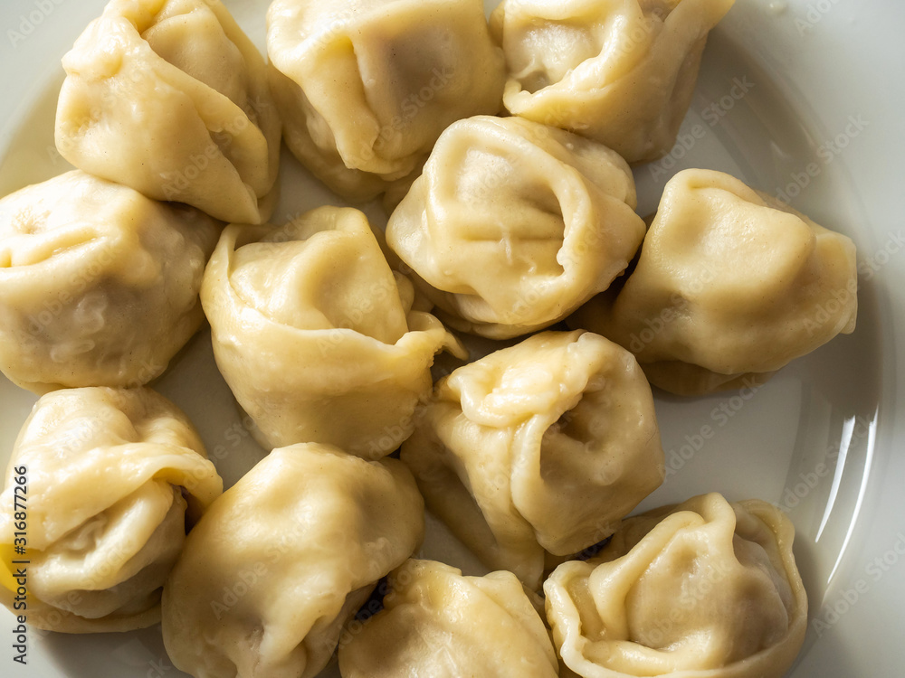 Portion of traditional Russian cooked dumplings on a white plate. Close up.