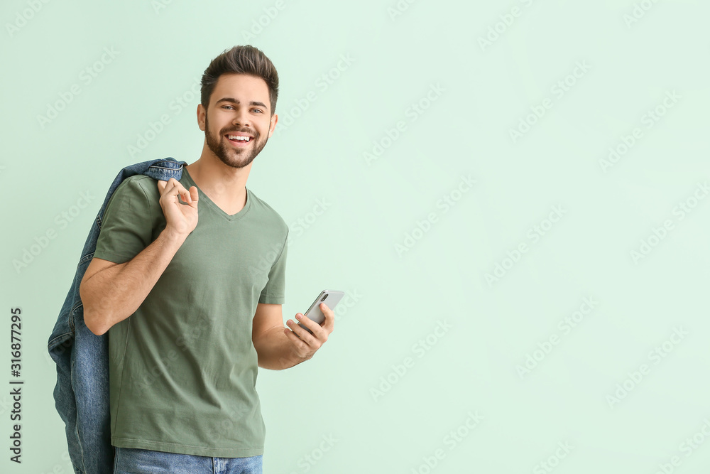 © Pixel-Shot - Happy young man with mobile phone on color background