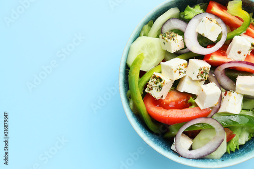 Bowl of tasty Greek salad on color background