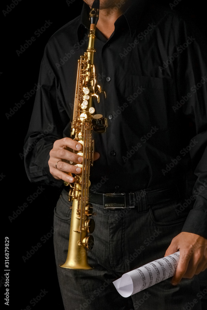 Naklejka premium soprano saxophone in hands on a black background