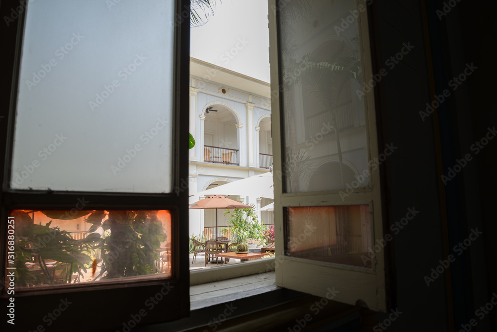 View of an inner garden from behind a window, in a dark room. Background in focus