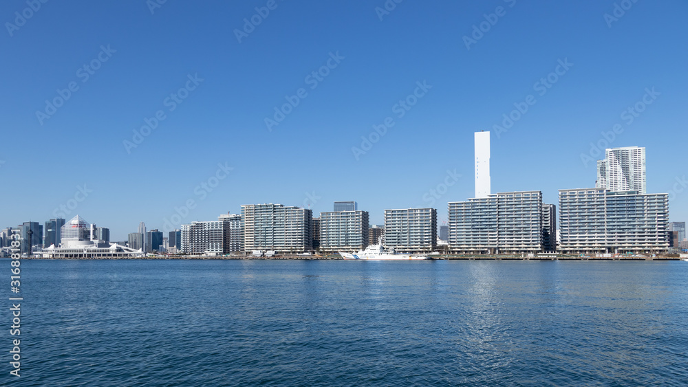 青空を背景に豊洲ふ頭から見た東京湾岸のビル群と選手村