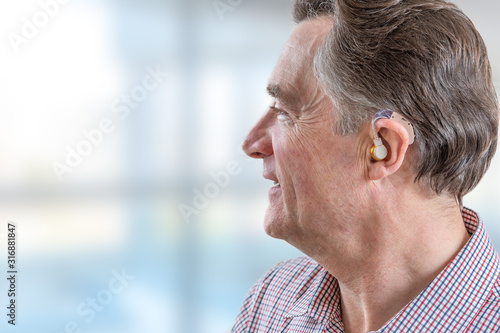 head of a senior man with hearing aid in his ear photo
