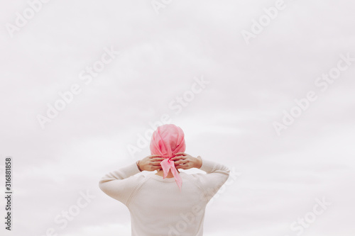 Stock photo of a woman with a pink handkerchief on her head. She has cancer