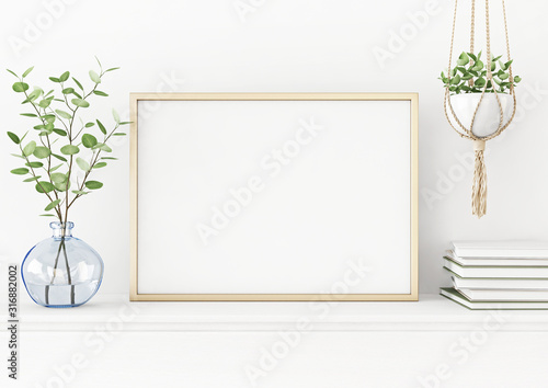 Interior poster mockup with horizontal gold metal frame on the table with plants in blue vase and hanging macrame pot on empty white wall background. A4, A3 size format. 3D rendering, illustration.