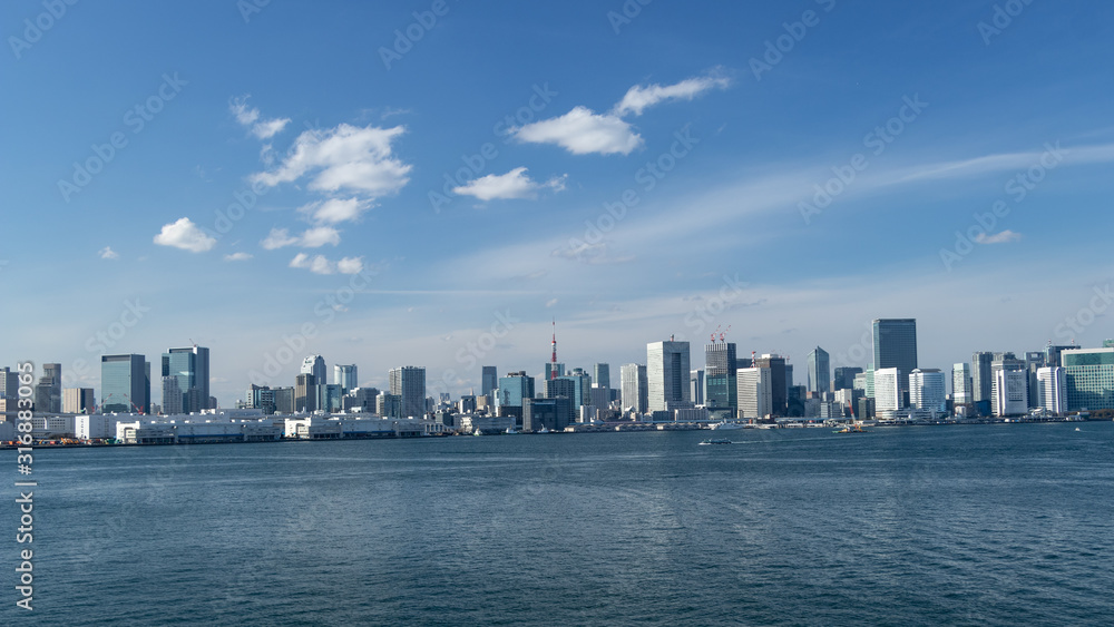 青空を背景にレインボーブリッジから見た東京湾岸のビル群