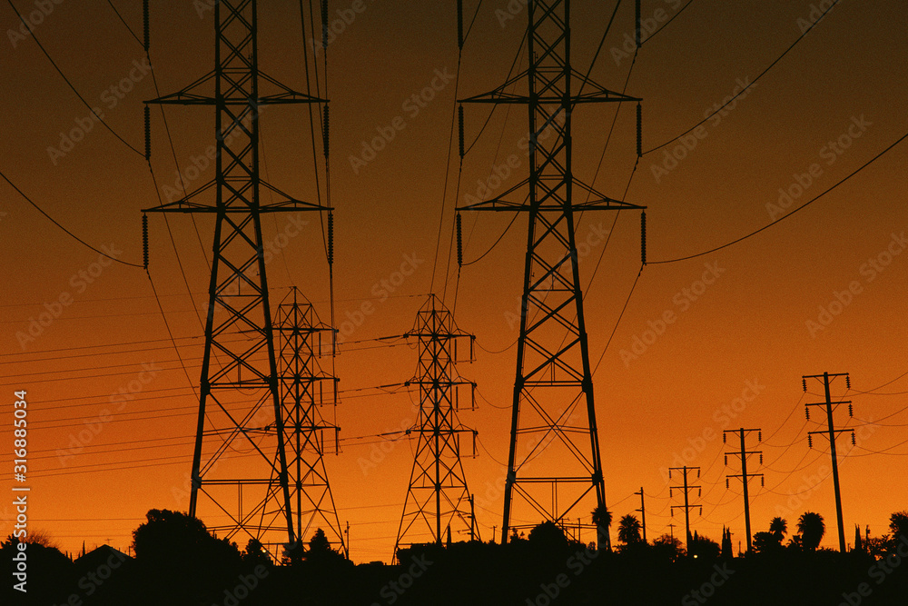 Fototapeta premium Power lines silhouetted by setting sun