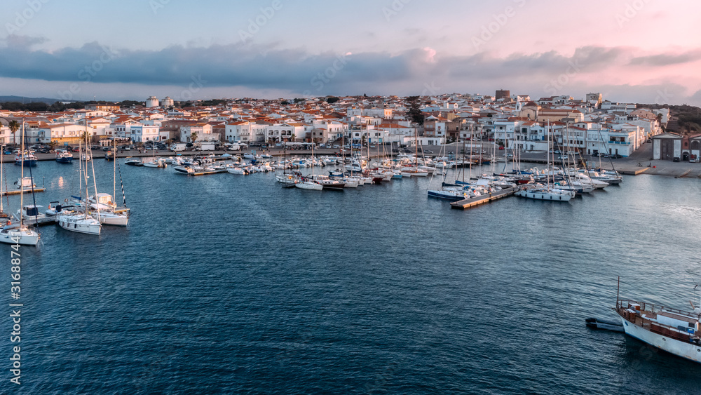 Widescreen aerial view of lagoon with moored boats and yachts. Blue color of sea. Drone photo. Beauty cloudy sunset on Sardinia, Mediterranean island. Vacation and tourism concept.