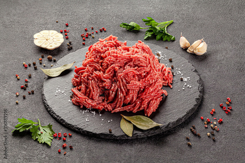 Raw meat products. Veal or mixed homemade minced meat with spices on a black background. board background image, copy space text photo