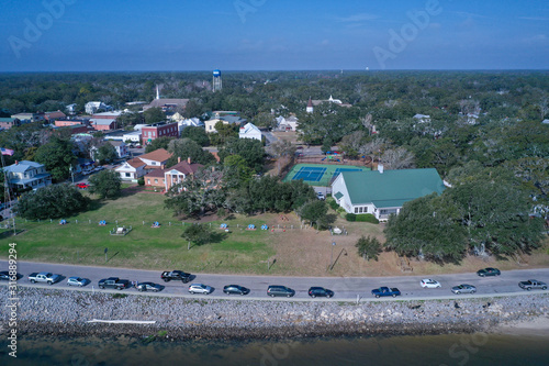 Aerial view of Southport North Carolina water front. Cars line the road along the Cape Fear River. Over the water looking back at the town.