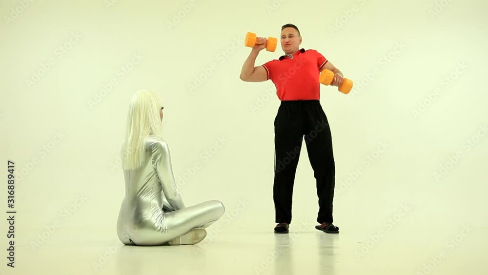 Robot girl and man doing physical exercises with dumbbells watching at girl. Push up. Humor, funny Robot girl and man doing physical exercises with dumbbells watching at girl. Push up. Humor, funny