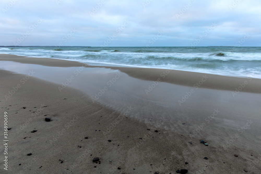landscape of wide sandy beach by the cold Baltic sea in cloudy weather at long exposure landscape of wide sandy beach by the cold Baltic sea in cloudy weather at long exposure