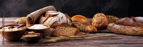 Assortment of baked bread and bread rolls and cutted bread on table background