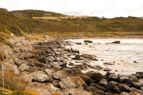 Scenic view of a rocky shore surrounded by hills covered in deserty greenery photo