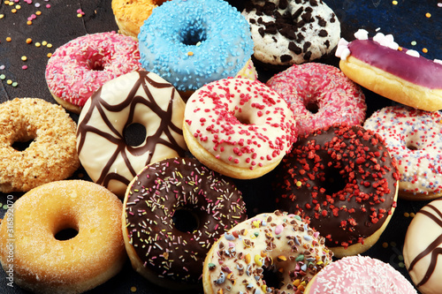Photo assorted donuts with chocolate frosted, pink glazed and sprinkles donuts