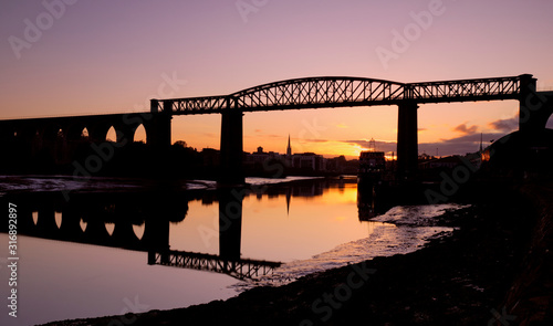 Fototapeta Naklejka Na Ścianę i Meble -  Orange and purple sunset on the town of Drogheda through the Boyne Viaduct seen from river banks