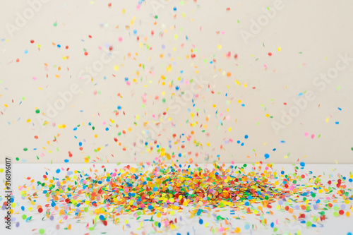 flying colored confetti on a beige background