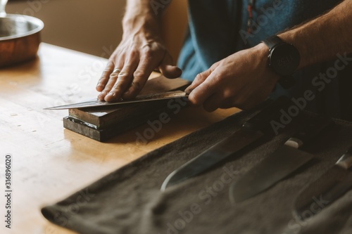 Person sharpening knives with a whetstone in the kitchen