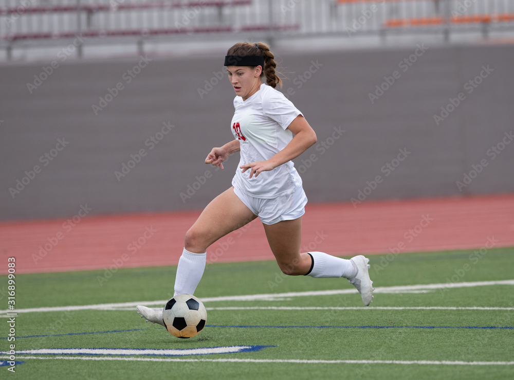 Fototapeta premium Young athletic girl playing in a soccer match