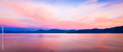 Wide background panorama of a brilliant colorful sky reflecting off water at sunset photo