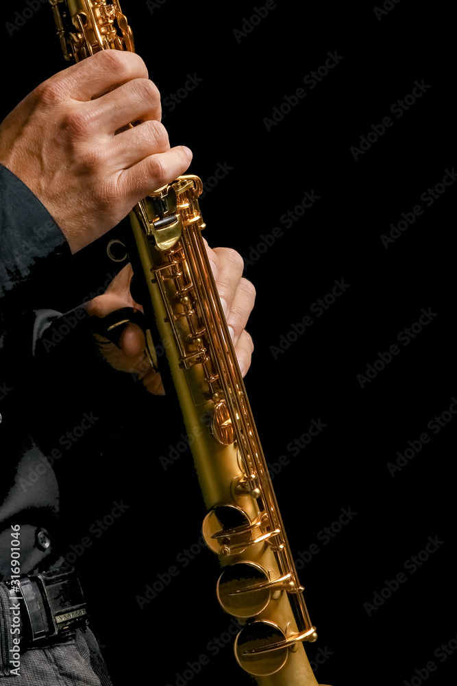Naklejka premium soprano saxophone in hands on a black background
