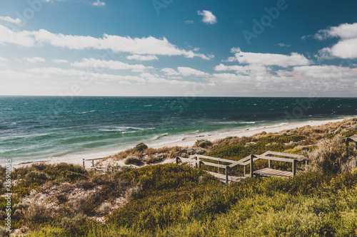 view of Cottesloe beach near Perth with thick vegetations and staircases leading to the sandy shore