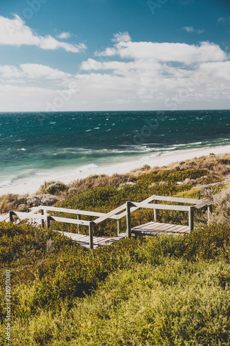 view of Cottesloe beach near Perth with thick vegetations and staircases leading to the sandy shore