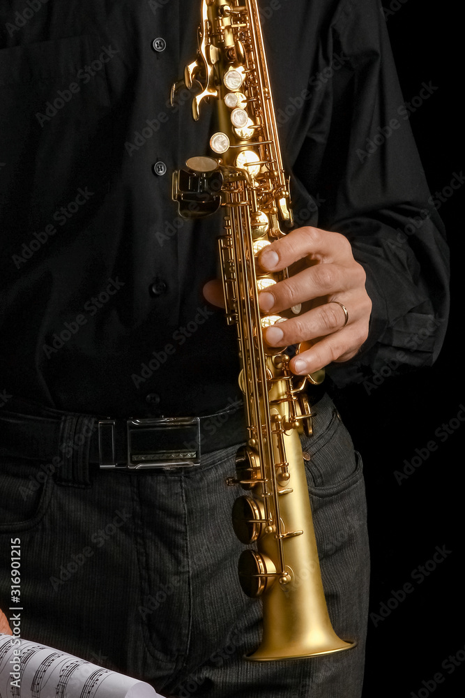 Naklejka premium soprano saxophone in hands on a black background