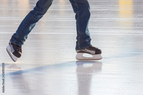 Legs of a man skating on an ice rink. Hobbies and sports. Vacations and winter activities. © photosaint