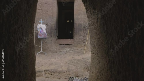 Forward push-in through tunnel to reveal entrance of the Bet Medhane Alem rock-hewn church in Lalibela, Ethiopia photo