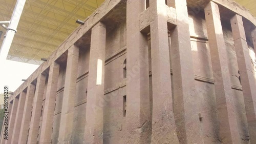 Pan right and tilt up view of rear exterior of Bet Medhane Alem rock-hewn church in Lalibela, Ethiopia