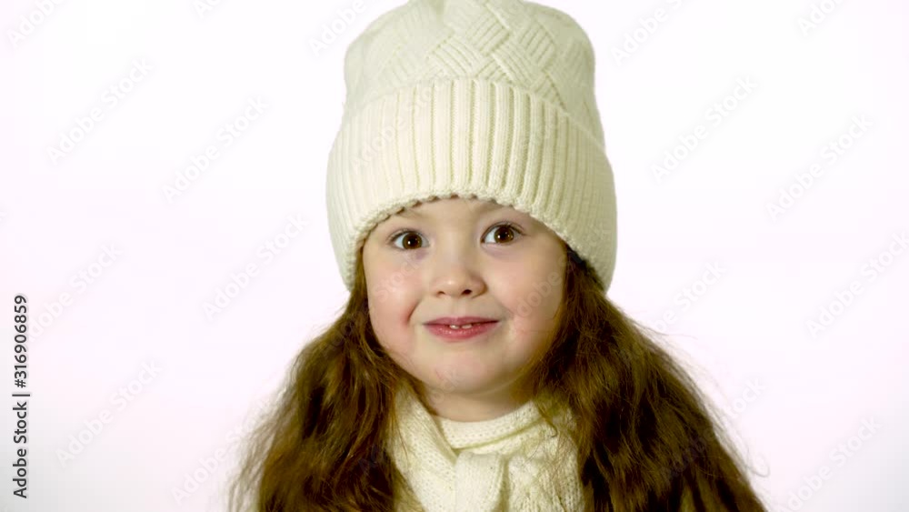 Little girl in a white knitted hat. Beautiful little girl in cap and scarf isolated on white. Little girl in a white knitted hat. Beautiful little girl in cap and scarf isolated on white.