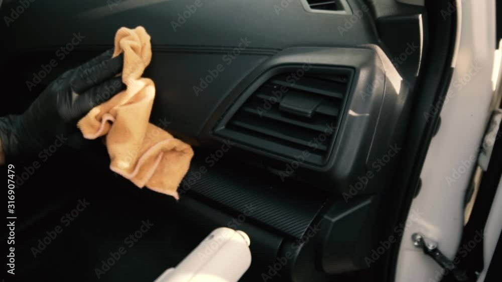 Male wearing black gloves cleaning a dashboard side air vent with steam Male wearing black gloves cleaning a dashboard side air vent with steam