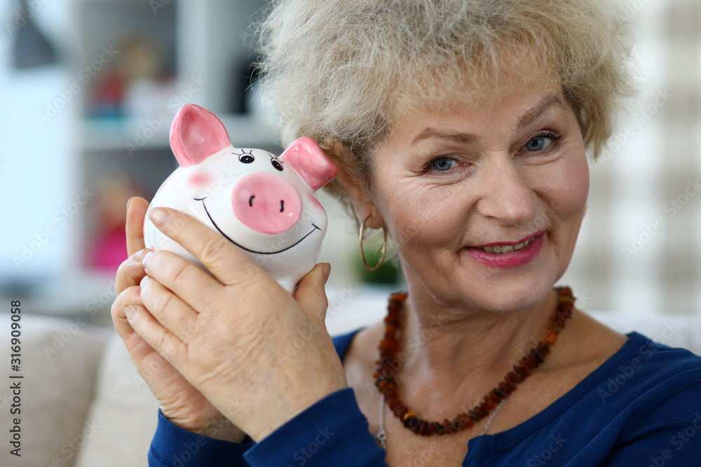 Φωτογραφία Portrait of cheerful aged grandmother with pink piggy bank