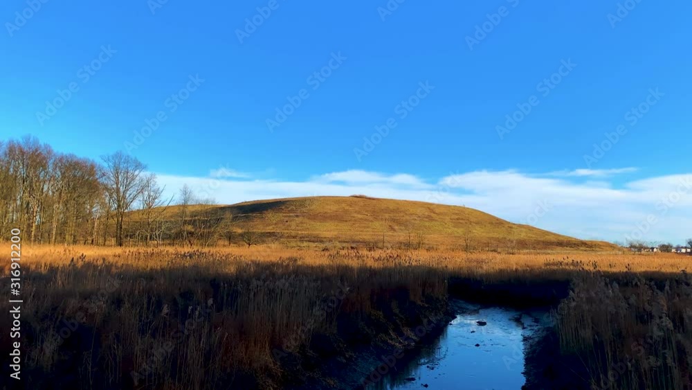 sunny day with blue sky, clouds on the horizon, small mountain in sight sunny day with blue sky, clouds on the horizon, small mountain in sight