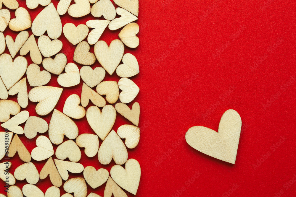 Obraz premium Romantic background of dozens of tiny wooden hearts with a single heart on a red card. For love, romance, or Valentine's Day. With blank space for text.