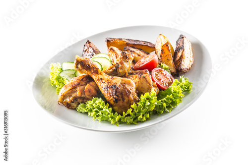 Roasted chicken legs with lettuce salad potatoes and tomatoes isolated on white